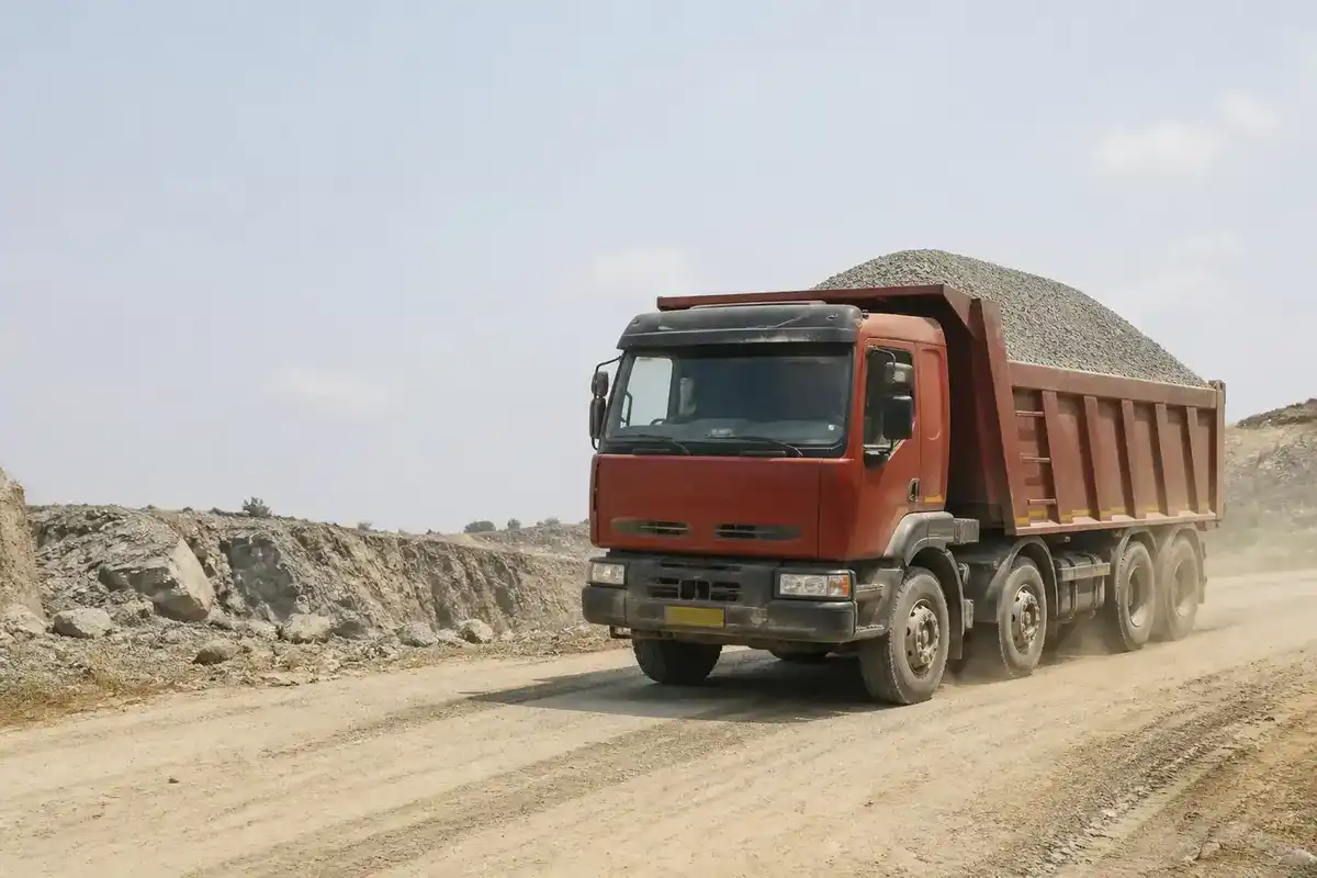 Loaded Indian tipper truck leaving a quarry on a dusty road