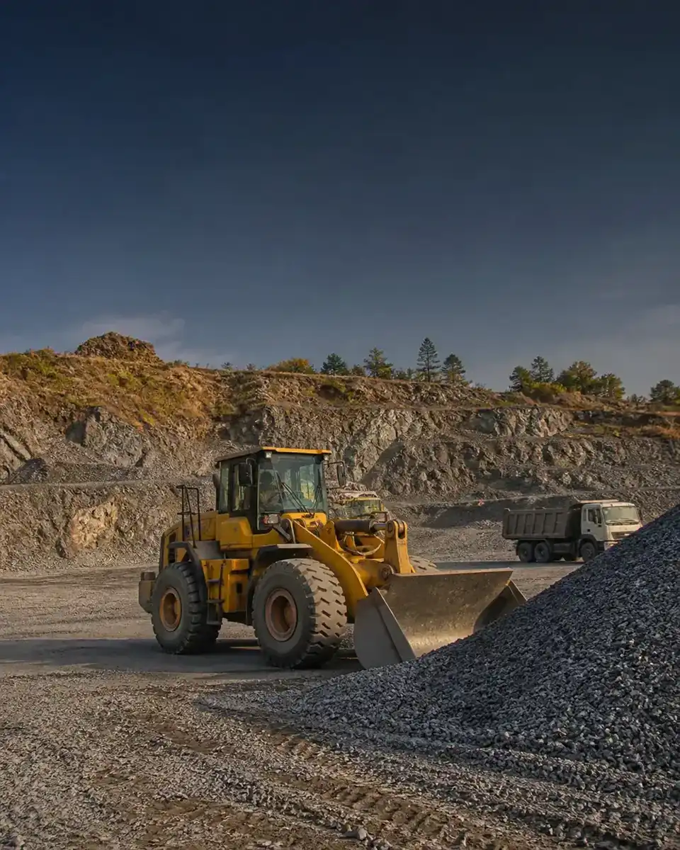 Wheel loader facing a crushed-stone pile at an Indian quarry